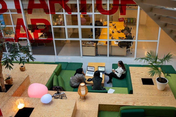 Arbeid og samtaler ved datamaskiner i Startuplabs lokaler.