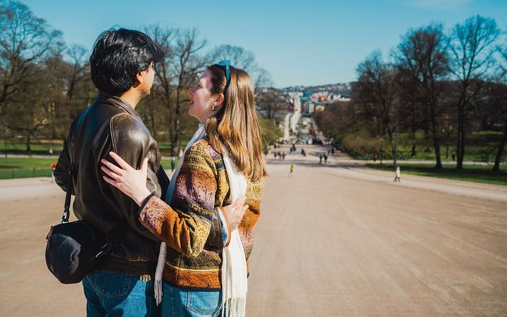 Et par som står på slottsplassen og ser nedover Karl Johan i Oslo