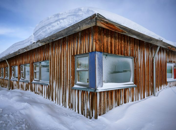 Trehus med snø og is i Varangerbotn, Norge