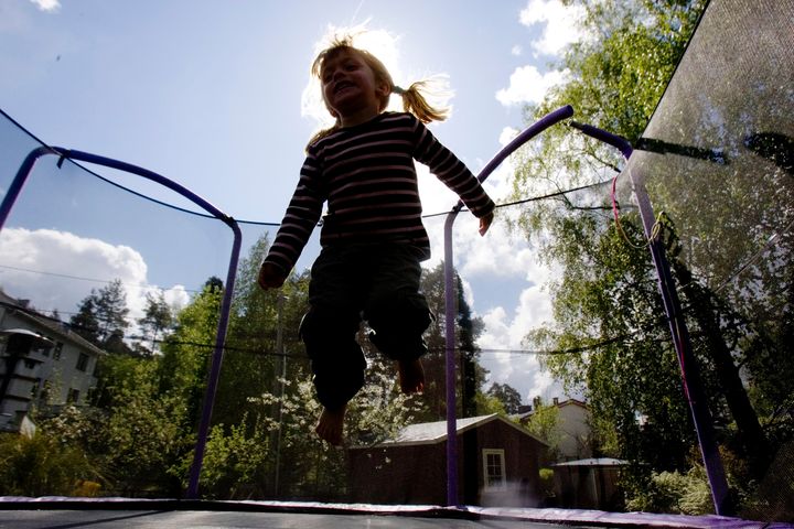 Et barn hopper på en trampoline med sikkerhetsnett.