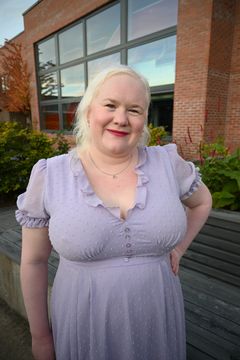 En smilende kvinne med hvitt hår og lavendelfarget kjole