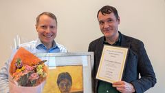 To menn smiler. De holder blomster, bilde og et diplom