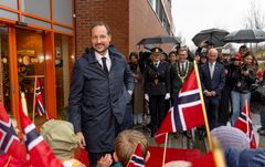 En smilende Kronprins Haakon utenfor Hurdal syn- og mestringssenter. Foran han står det barnehagebarn med flagg.