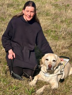 Dame sitter på plenen med lys labrador