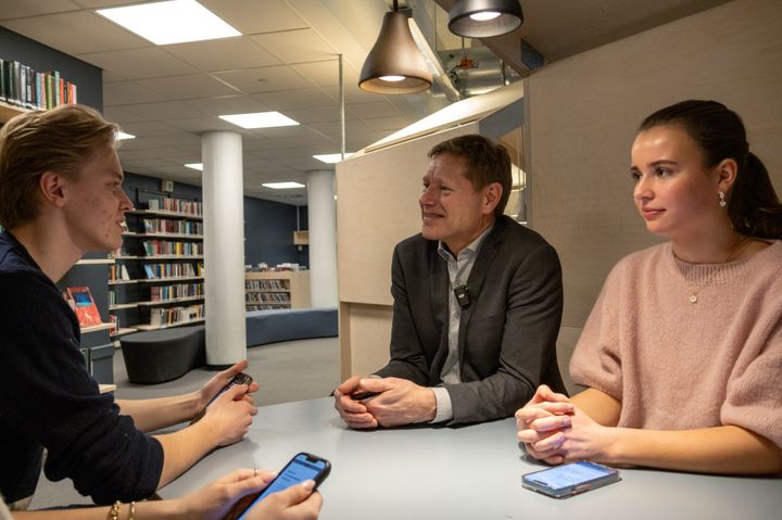 Ungdommer tester ny utvekslingstjeneste med en direktør ved et skolebord.