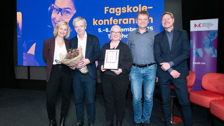 Sveinung Skule og Sigrun Aasland sammen med glade representanter, som holder diplom og blomster, fra Fagskulen Vestland på scenen under Fagskolekonferansen 2025.