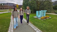 Emmy Wang, Benedikte Digernes og Gabriel Våge Barstad går sammen på universitetsområdet ved UiT i Tromsø. UiT-skiltet er synlig ved siden av dem.