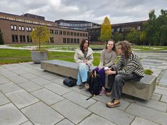Emmy Wang, Benedikte Digernes og Gabriel Våge Barstad sitter sammen utendørs på universitetsområdet ved UiT i Tromsø.