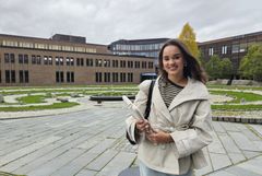 Emmy Wang står utendørs på universitetsområdet ved UiT i Tromsø og smiler mot kamera.