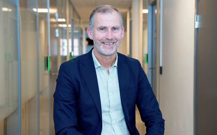Sigurd Eriksson sitter i en kontorgang og smiler mot kameraet.