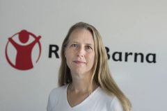 Kaja Hegg står foran Redd Barna-logoen og ser mot kameraet.
