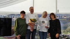 Gruppen poserer med utmerkelsen for osten Geiteberget. En person holder en blomsterbukett, en annen holder diplomer.