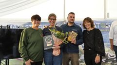 Fire personer står sammen, en holder en pris og en annen har blomster.