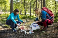 To personer plukker søppel i en skog.