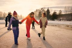 Ei jente står på skøyter og holder to venninner i hånda for støtte