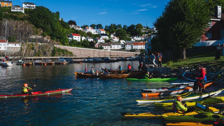 Padlere, roere og seilere ankommer bystranda i Arendal under Arendalsuka, etter å ha reist sjøveien fra Holmestrand og Lindesnes.
