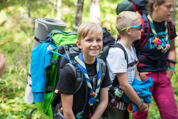 En speidergutt i skogen smiler