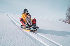 En kvinne og et barn aker full fart ned fra en bakke