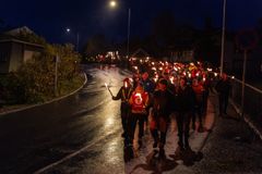 Et fakkeltog går langs veien i mørket