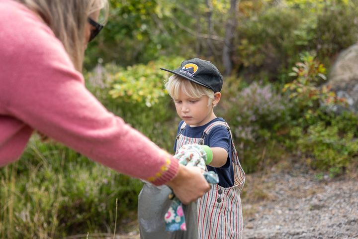 En gutt plukker søppel i skogen.